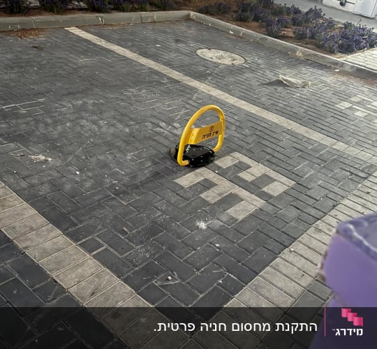 מחסום חניה אישי צהוב מותקן במרכז תא חניה מרוצף